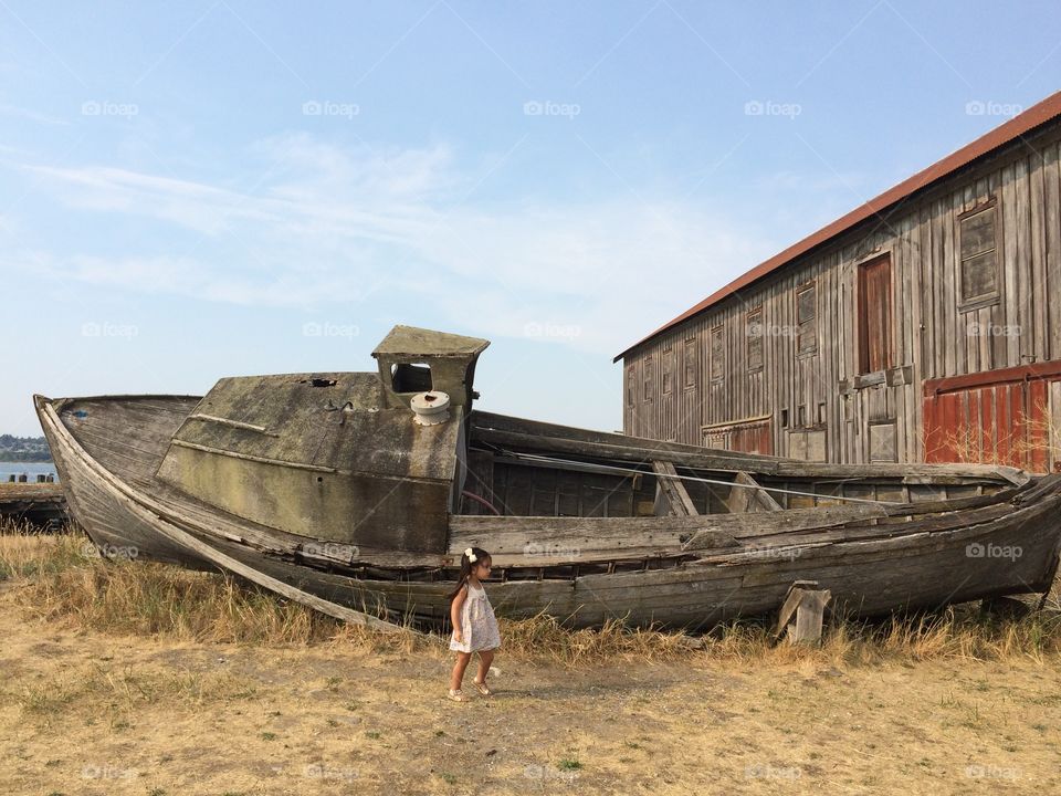 Little girl standing near wrecked ship