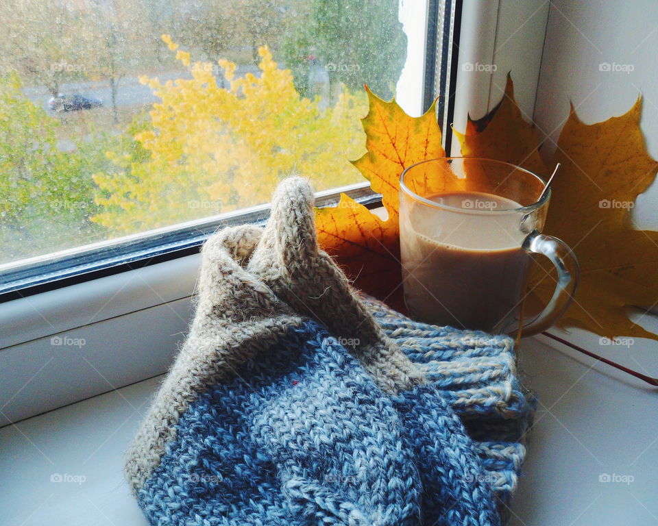 knitted warm socks, autumn leaves and a cup of coffee with milk