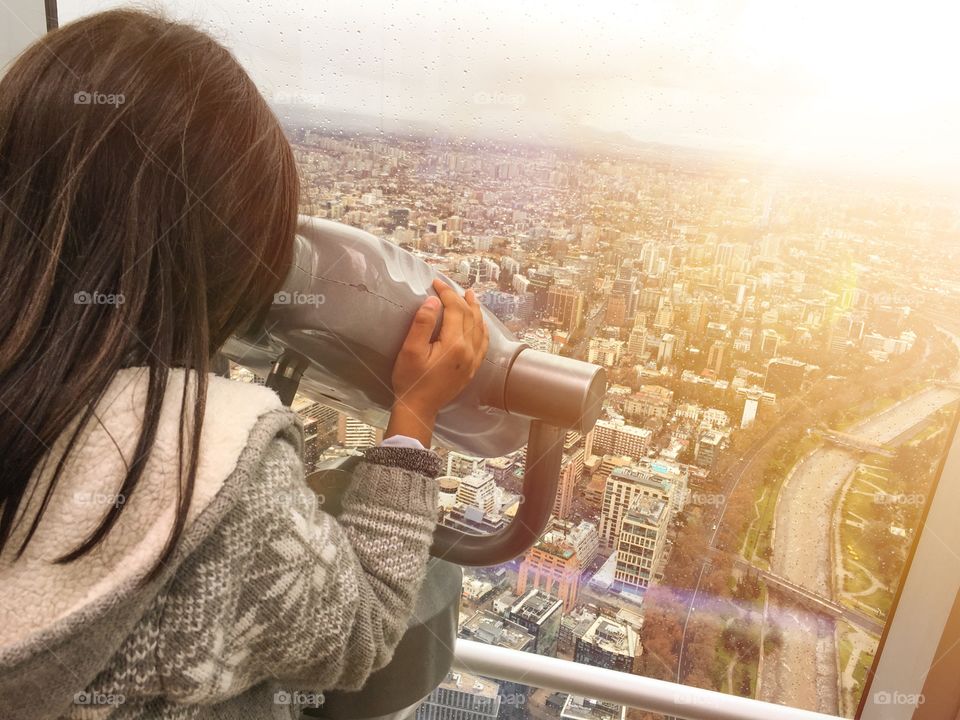 Little girl looking at the city through a binocular