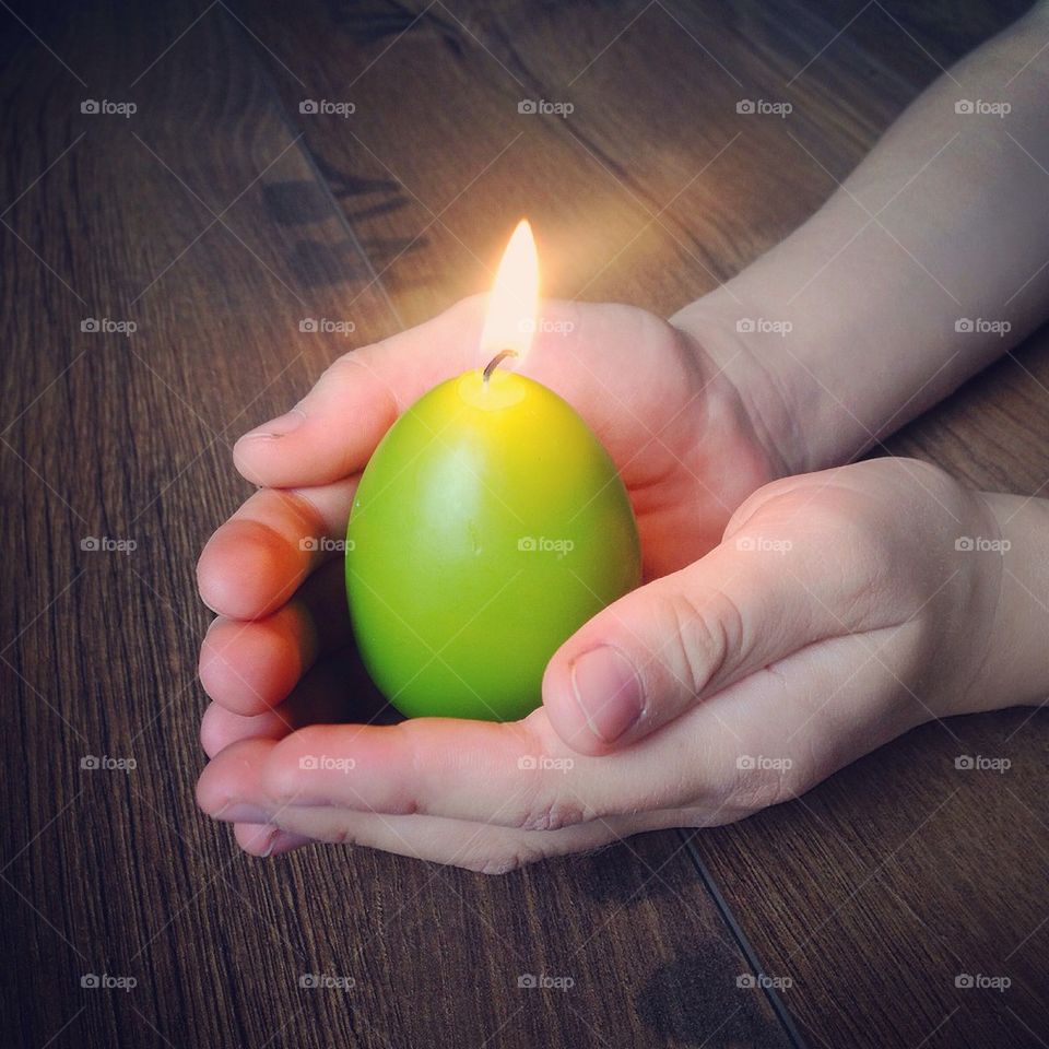 Close-up of a boy's hand with illuminated candle