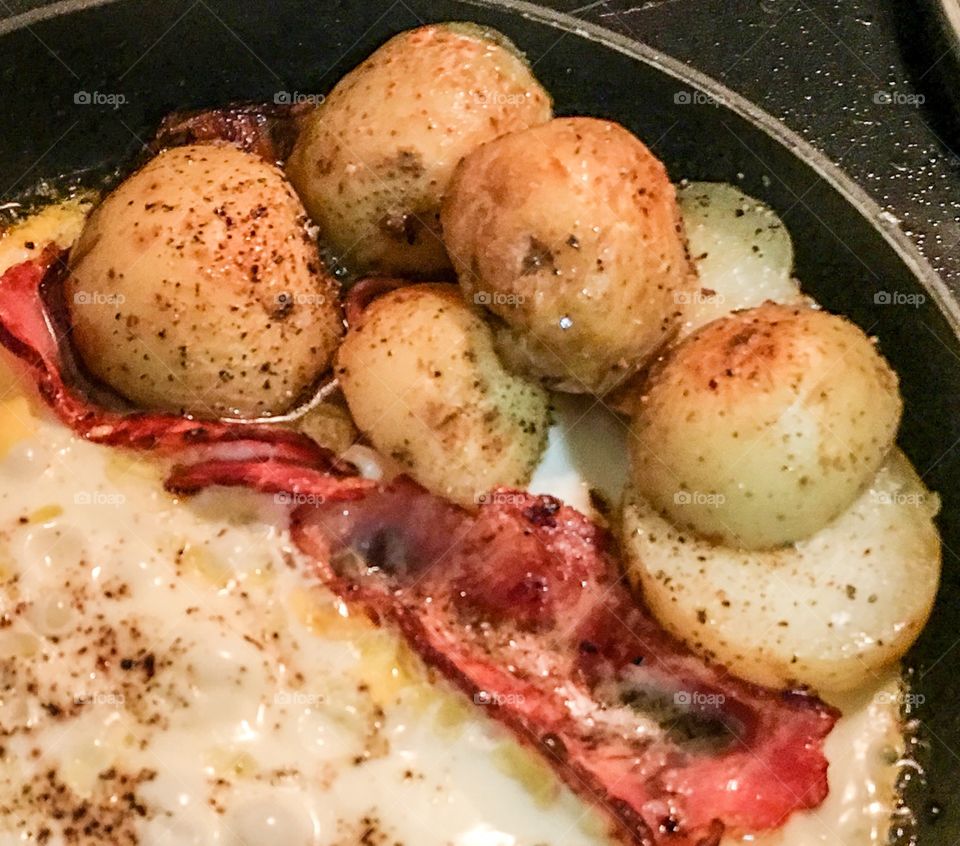 Breakfast plate of eggs, shortcut bacon, baby potatoes closeup in frypan