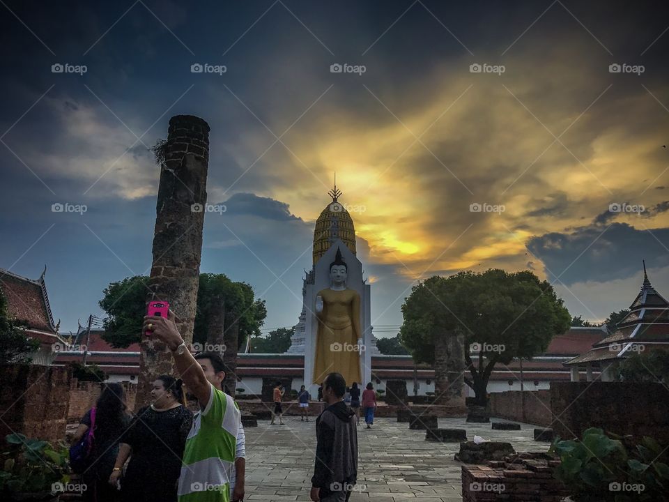 Tourists taking selfies in front of the Buddha at Phitsanulok, Thailand 