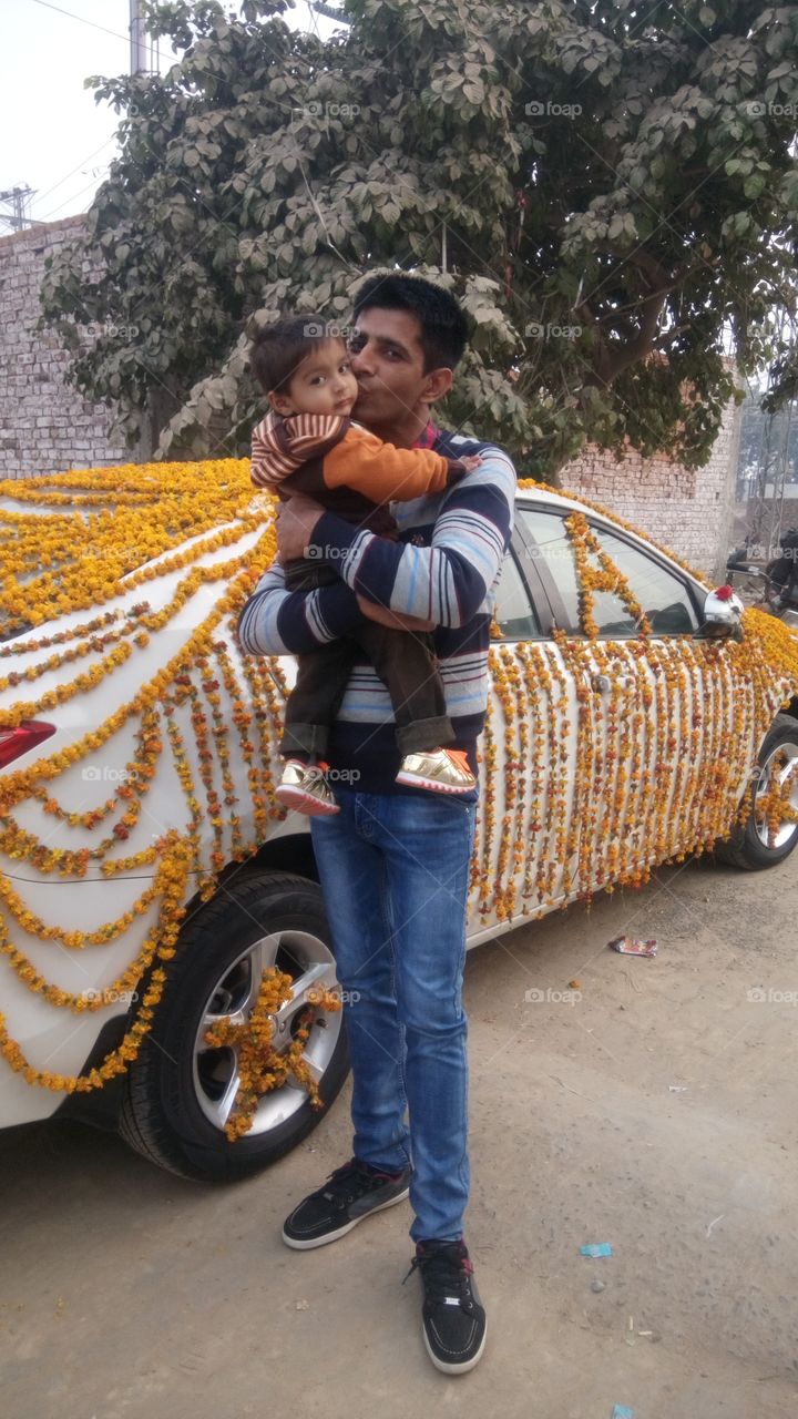 Father carrying loving his son standing near the decorated car