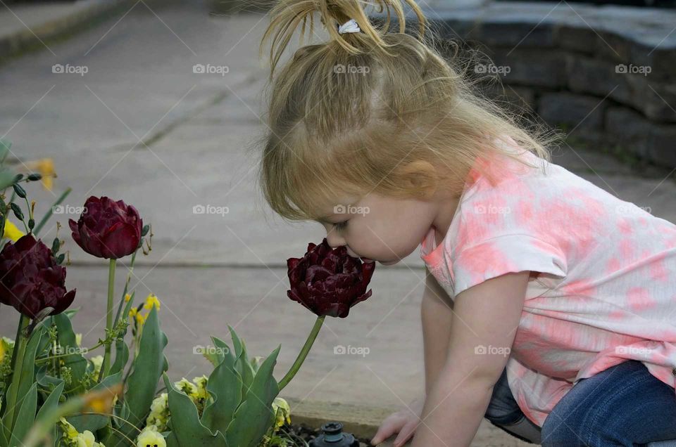 Cute girl smelling fresh flower in garden