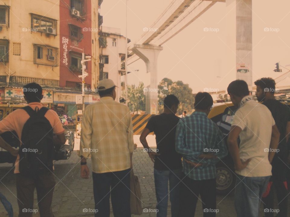 Friends waiting to cross a busy street in Mumbai