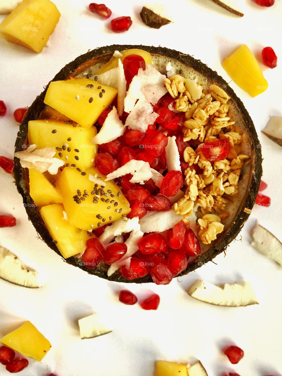 Tropical fruit breakfast, mango pomegranate coconut and granola served in a coconut shell 