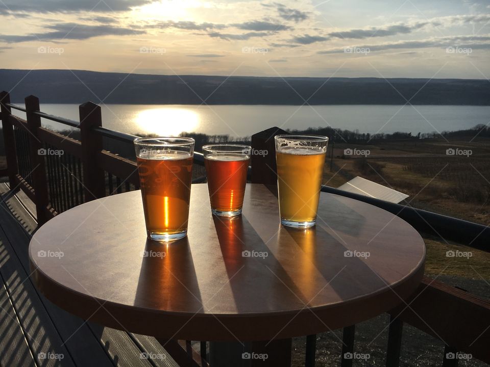 Beer glasses on table at lake side during sunset
