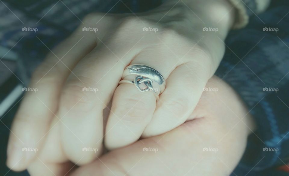 man and woman holding hands with wedding rings one in the shape of a heart in a faded glow for valentine's day