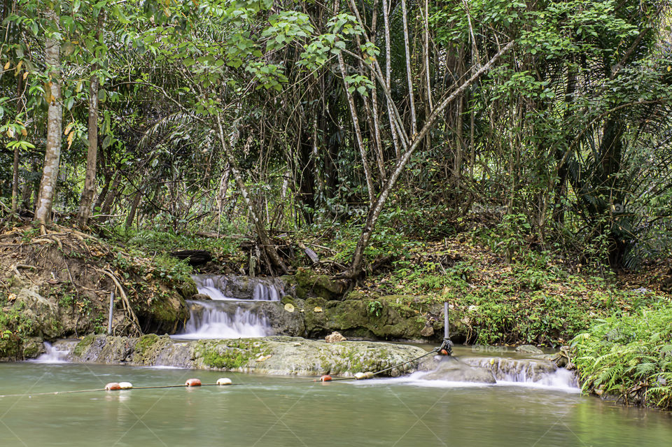 The water flowing over rocks and trees down a waterfall at Kapao waterfall National Park ,Chumphon in Thailand.