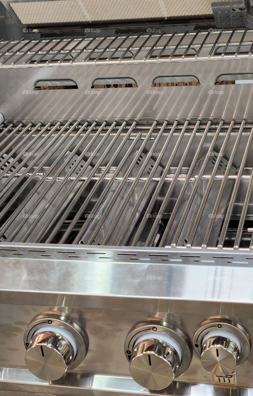 close-up of a shiny new stainless steel metal barbecue grill for sale in the Summer