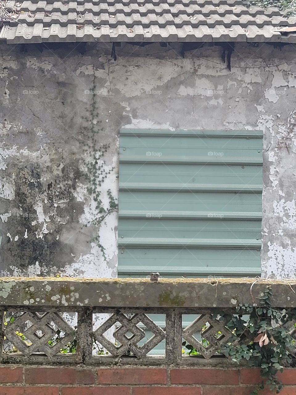 The mottled wall has iron sheets and a red brick fence outside the wall.