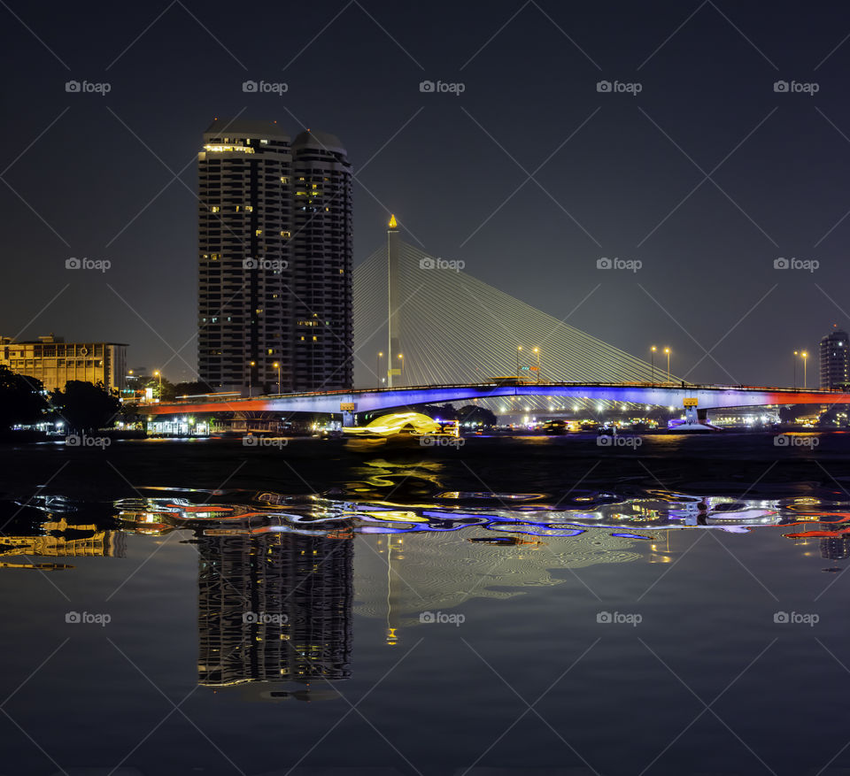 The beauty of the Chao Phraya River and boat at night with rationalism at Pinklao Bridge ,Bangkok Thailand.