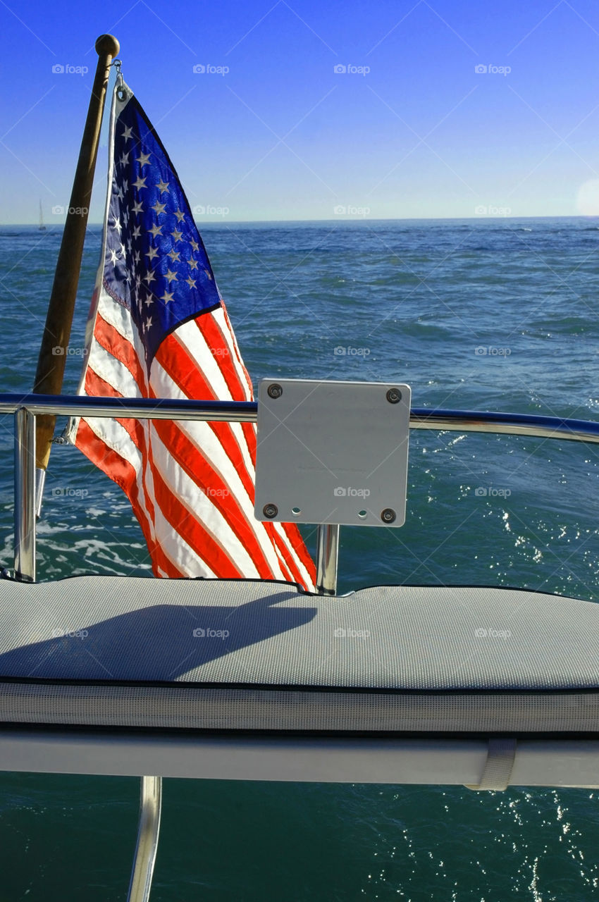 An American Flag stands proudly on the back of a sailboat. 