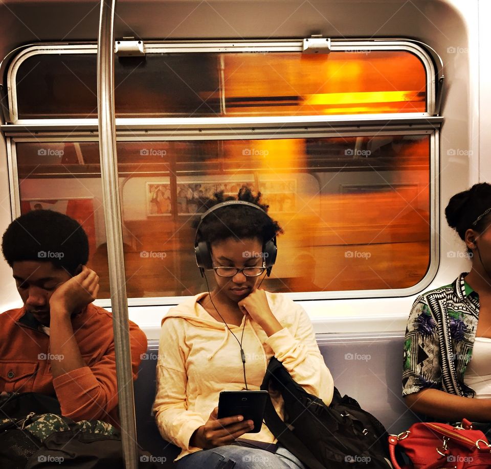 Woman in headphones reads a tablet on the subway in movement 