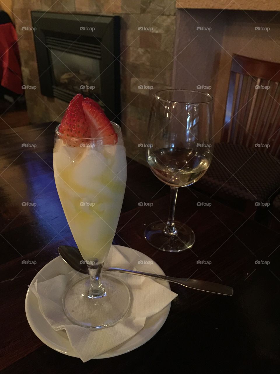 Stunning delicate limoncello gelato served in a champagne flute glass topped with strawberries; with a glass of Pinot Grigio.
