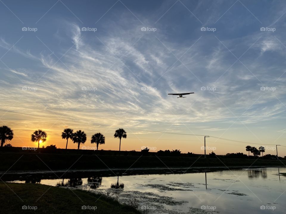 A small plane prepares to land as the beautiful sun prepares to set.