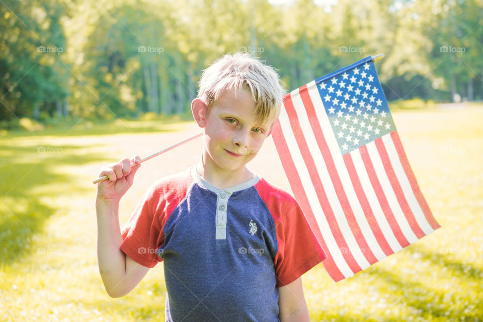 Young Boy in Red and Blue Shirt Carrying American Flag