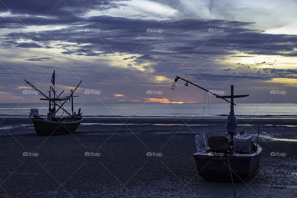 The morning sun light in the sea and the boat on the beach.