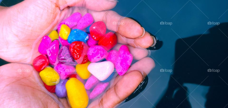 HOLDING MULTICOLOTED AQUARIUM STONES IN HAND UNDER WATER