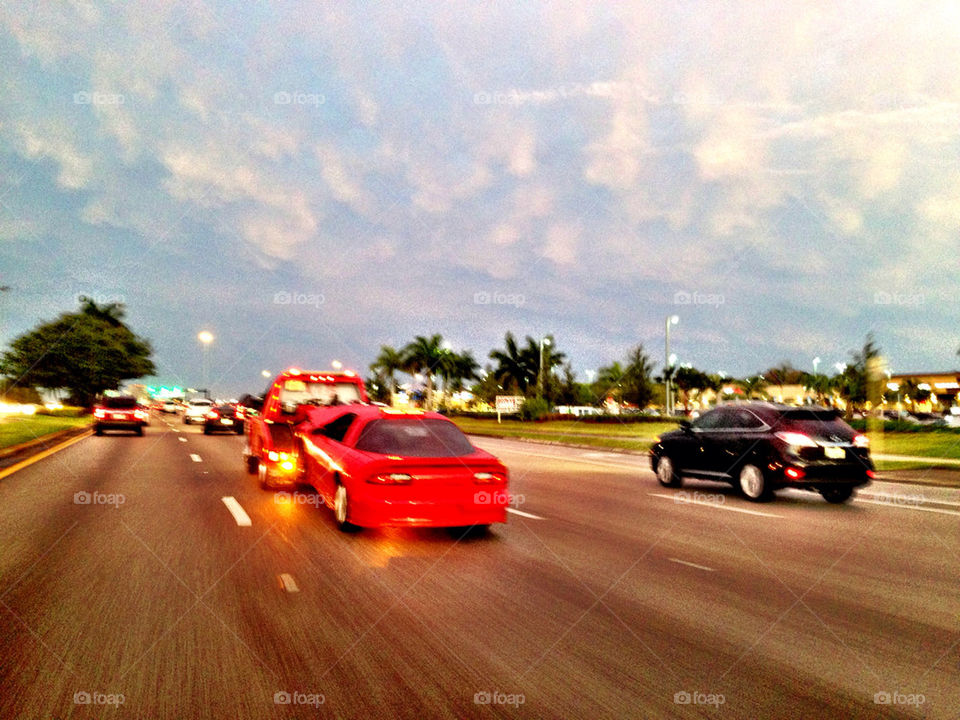 Towing truck. Red car being towed by red tow truck in highway, Miami