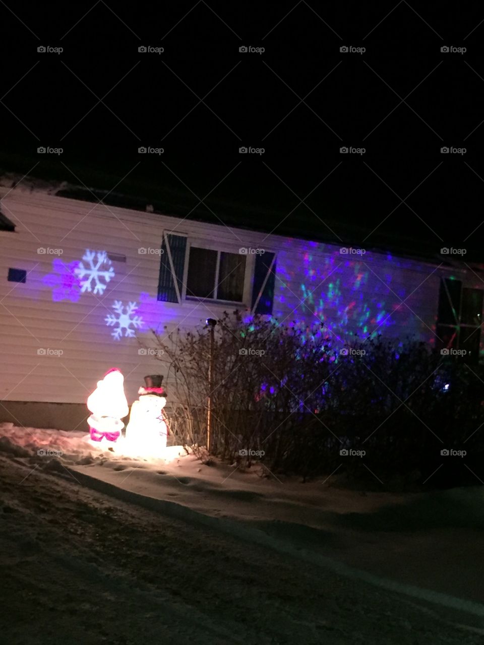 Small town Christmas charm snowman Santa Claus purple lights dancing on the house