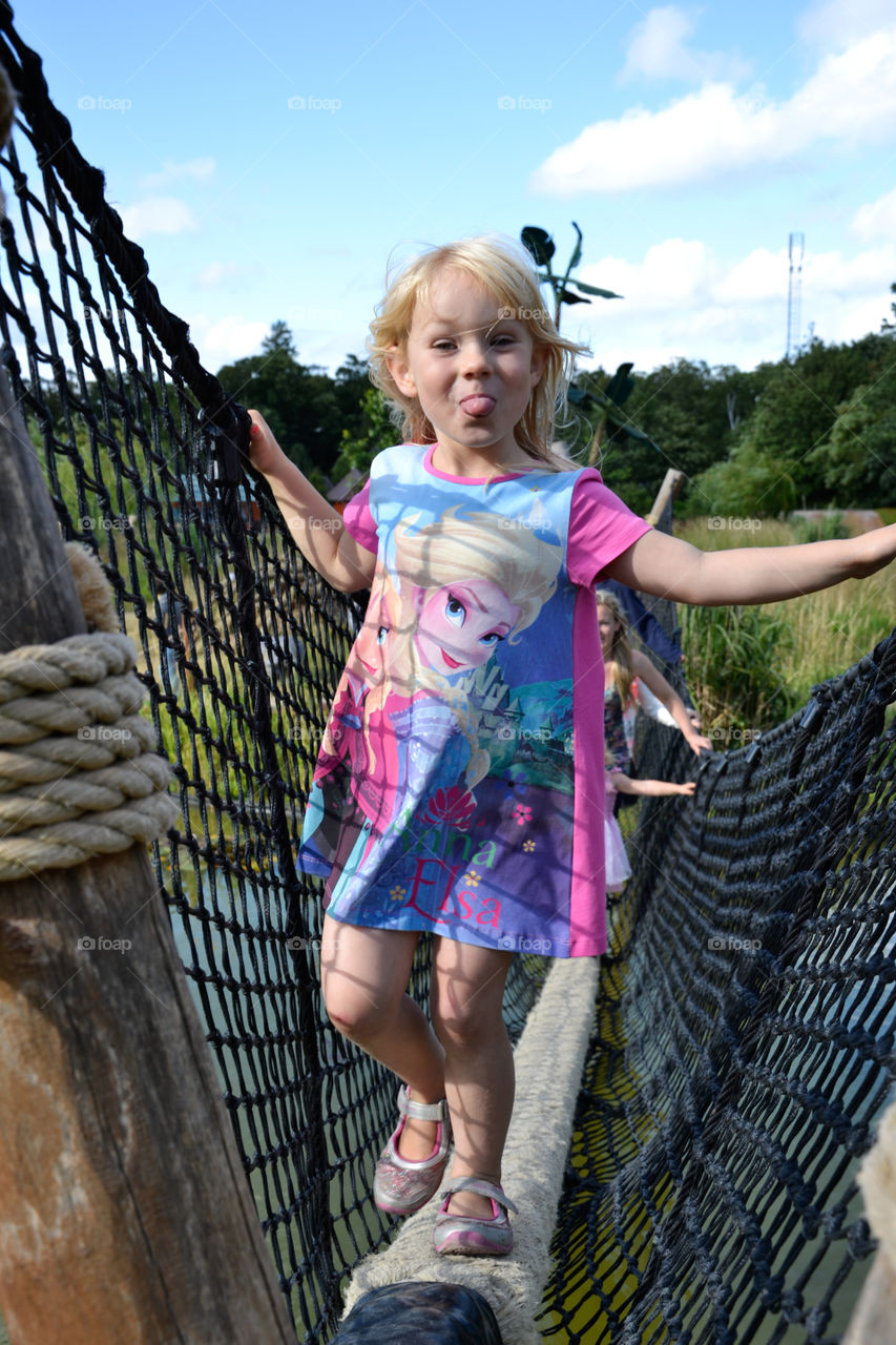 a girl of five years sticking out its tongue. playing on a playground in KnutBorg Zoo in Denmark.