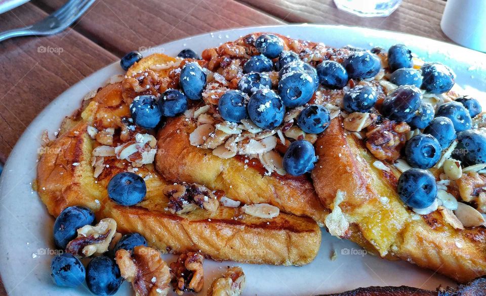 Luscious cinnamon French toast with candied walnuts, sliced almonds and fresh blueberries.
