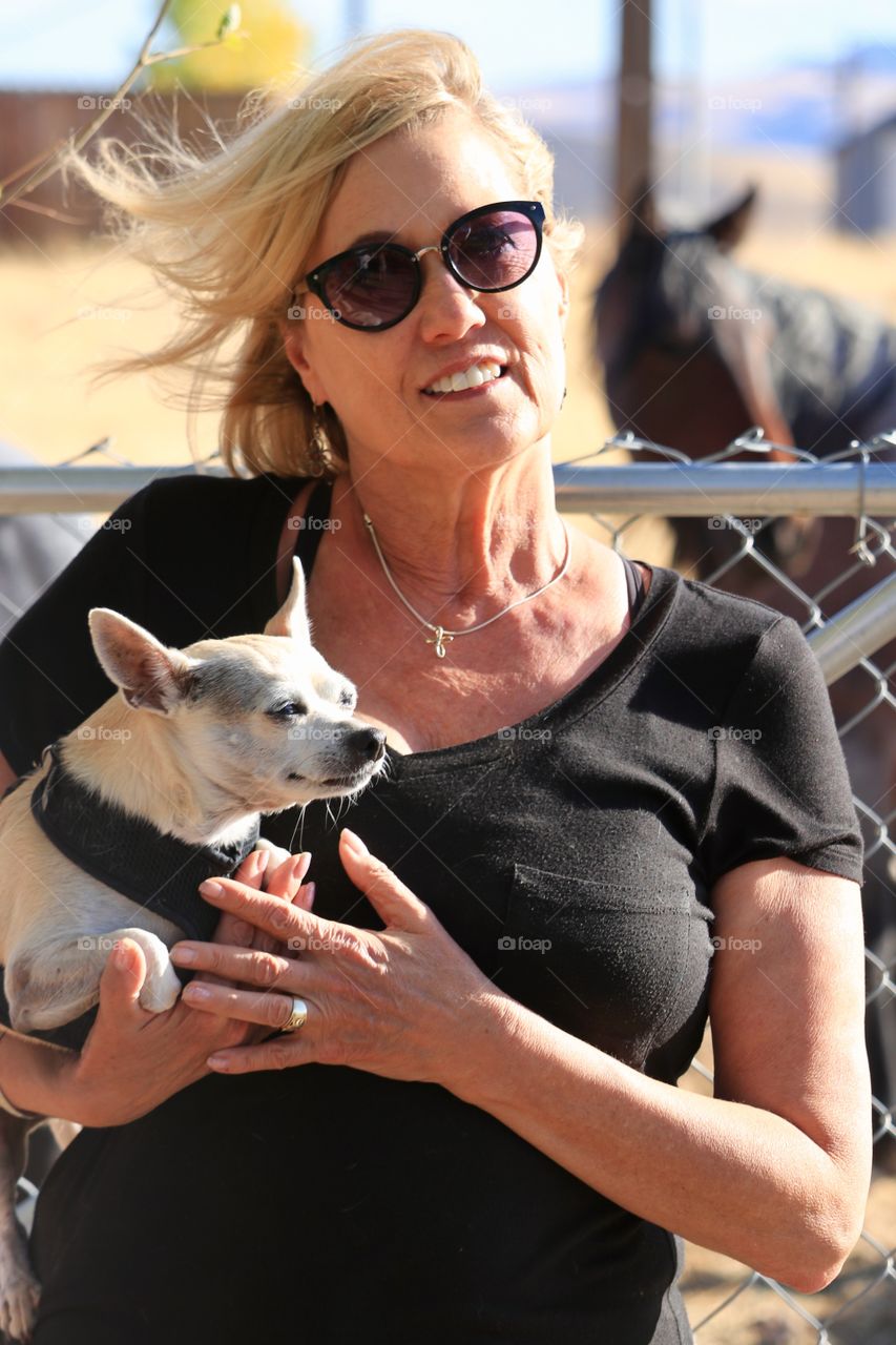 Middle aged attractive blonde woman holding chihuahua dog