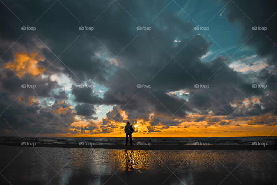 Silhouette of man with backpack during sunset