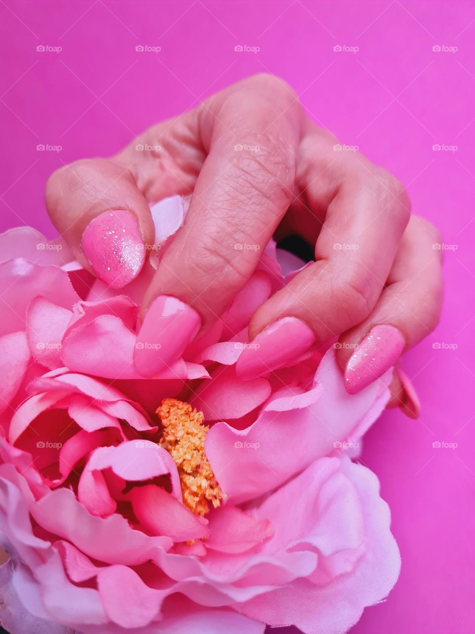 female hand with shocking pink semi-permanent nail polish performed with acrylgel technique