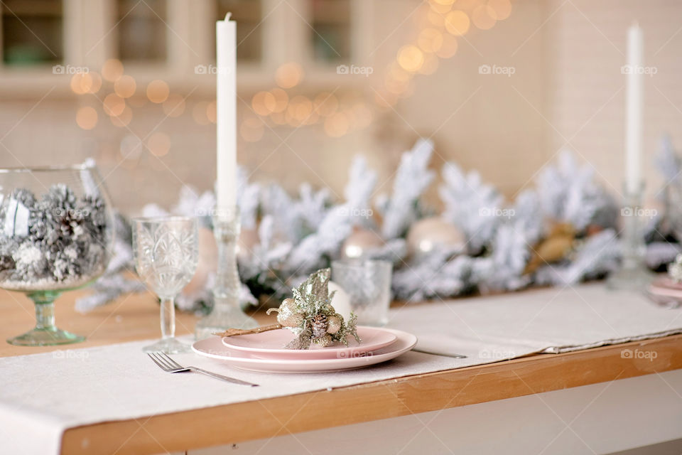 Festive winter cozy kitchen interior with garlands, decorations and gifts.  Christmas dinner at the decorated table.