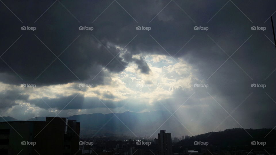 rayos del sol entrando a la ciudad a traves de una cavidad circular en las nubes