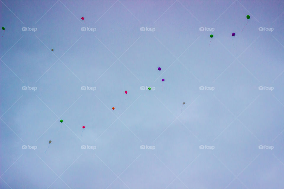 Multi colored balloons in a cmoudy sky