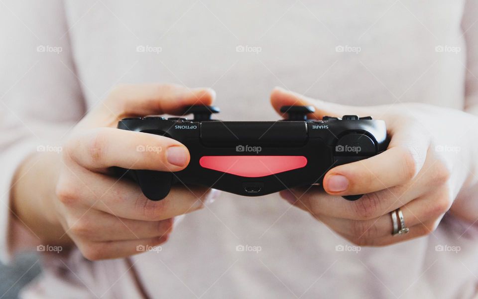 Close-up photo of woman holding a gamepad playing video games