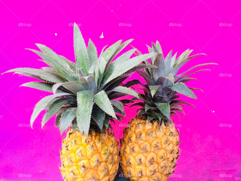 A yellow pineapple combination with a pink background