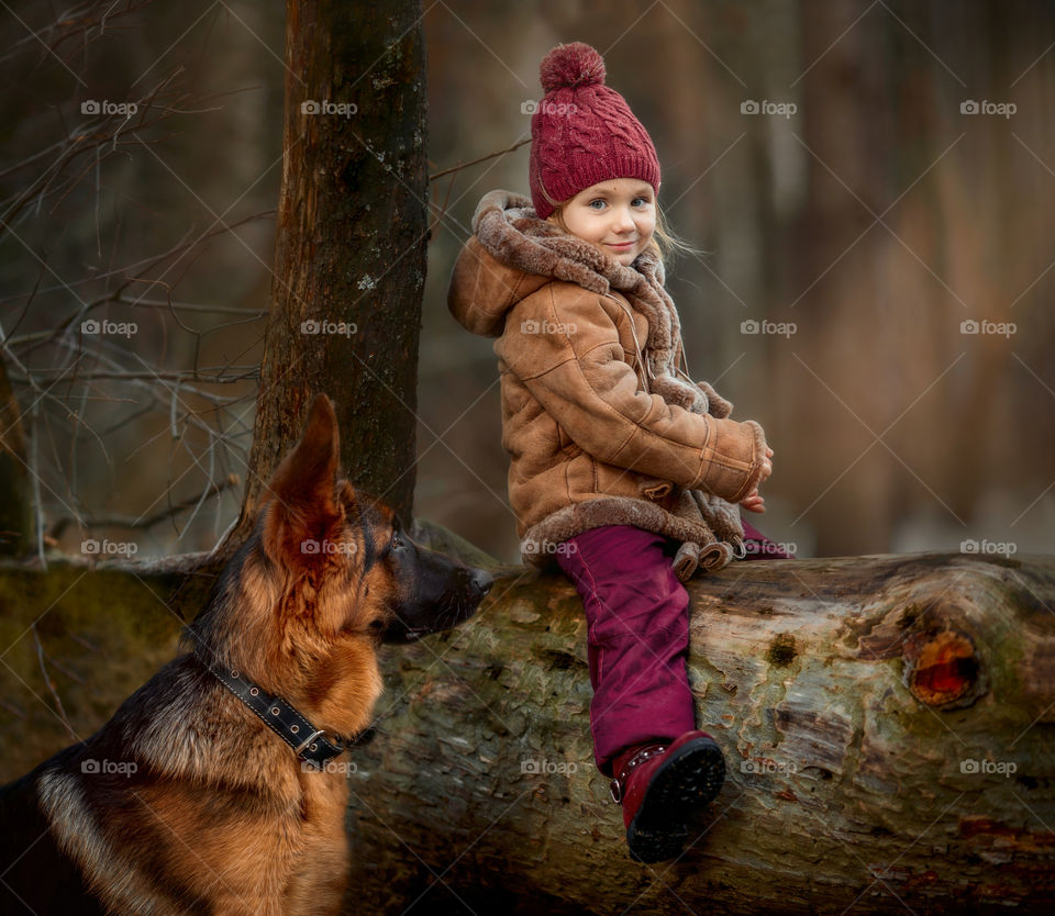 Little girl with German shepherd 6-th months puppy at early spring forest