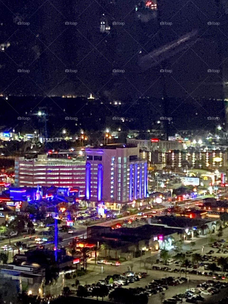 A nighttime view from above of colorful city lights and large buildings