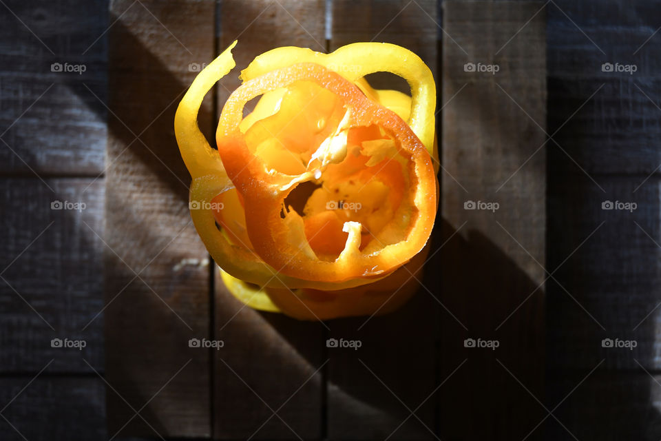 Yellow and orange peppers sliced and stacked up on each are seen in a flat lay in the brilliant sunlight.