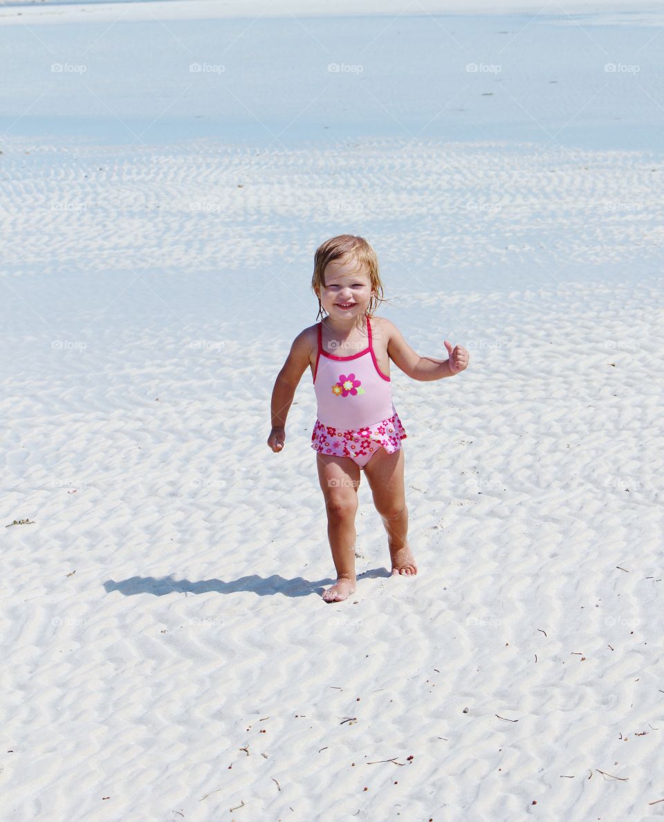 Little girl running in the sand at the beach