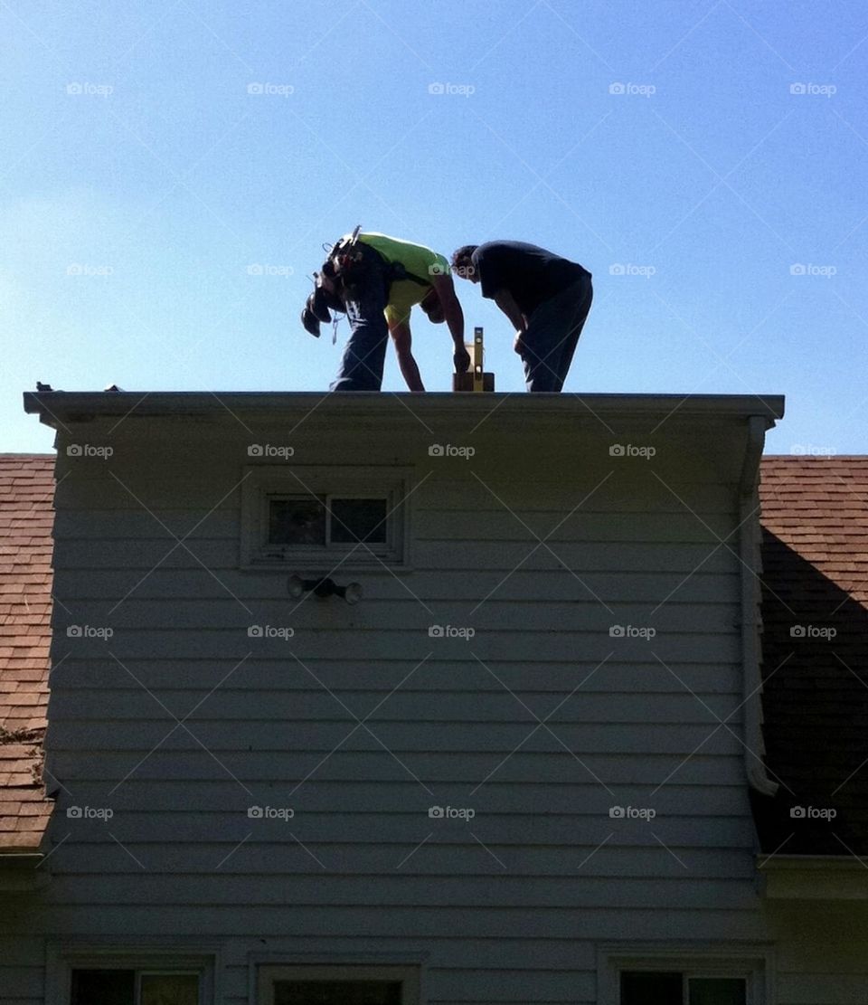 Two men on a roof making a  repair 