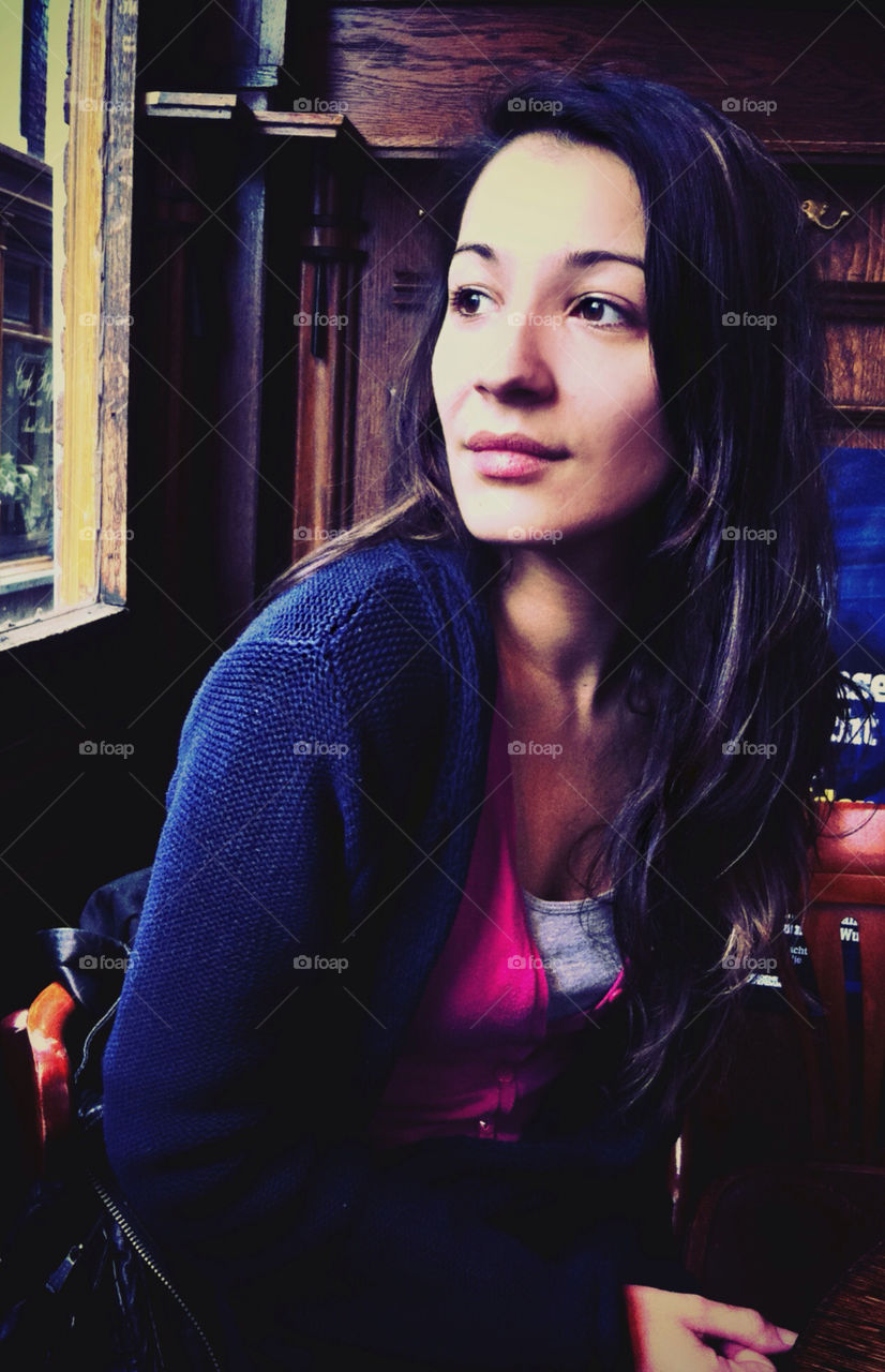 A woman sitting in a room, looking thoughtfully through an open