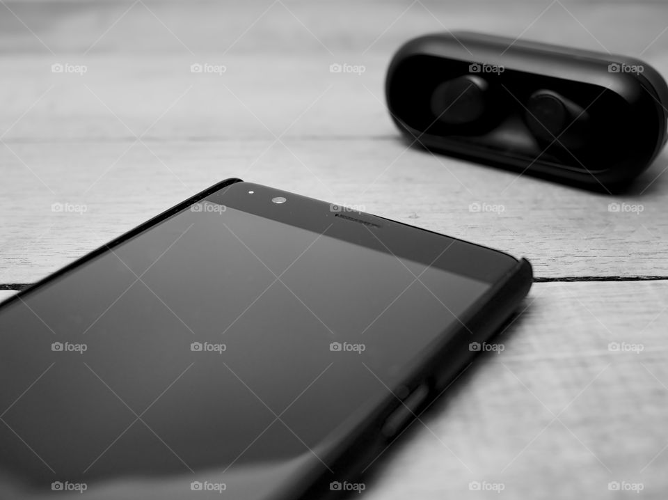 smartphone and wireless earphones in monochrome