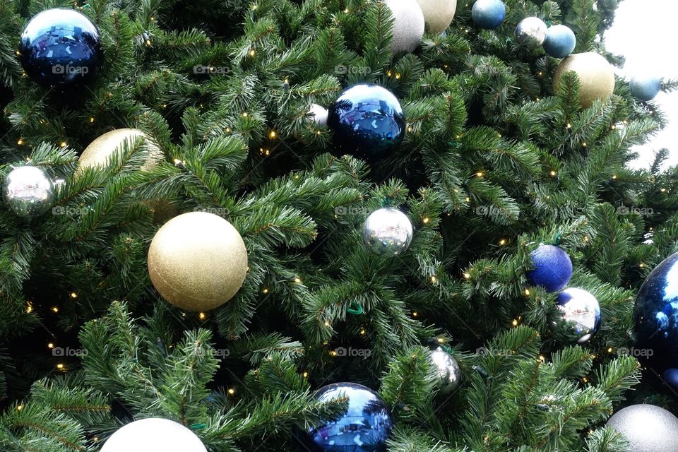 Close-up of Christmas tree where blue, gold and silver ornaments are decorated.