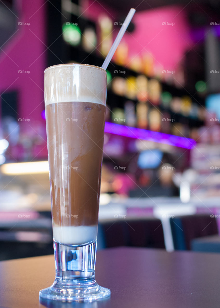 Greek style frappe in foreground with cafe setting blurred in background