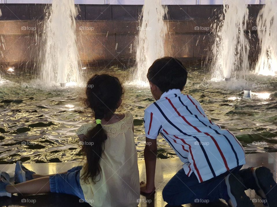 kids watching and enjoying by looking at water fountain at night