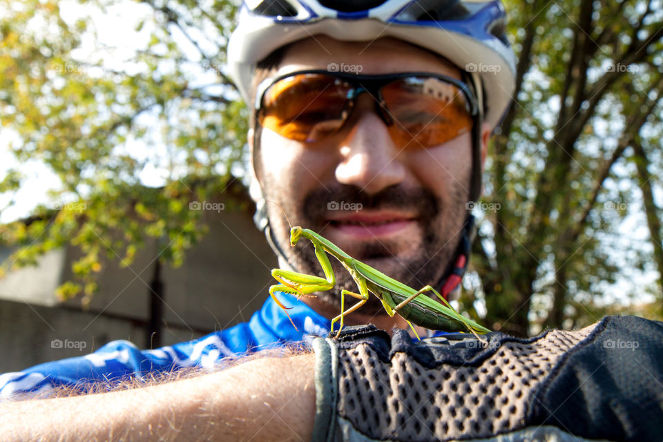 Friendship insect and man. Mantis on the hand. Bicycle form. Helmet, glasses, gloves.