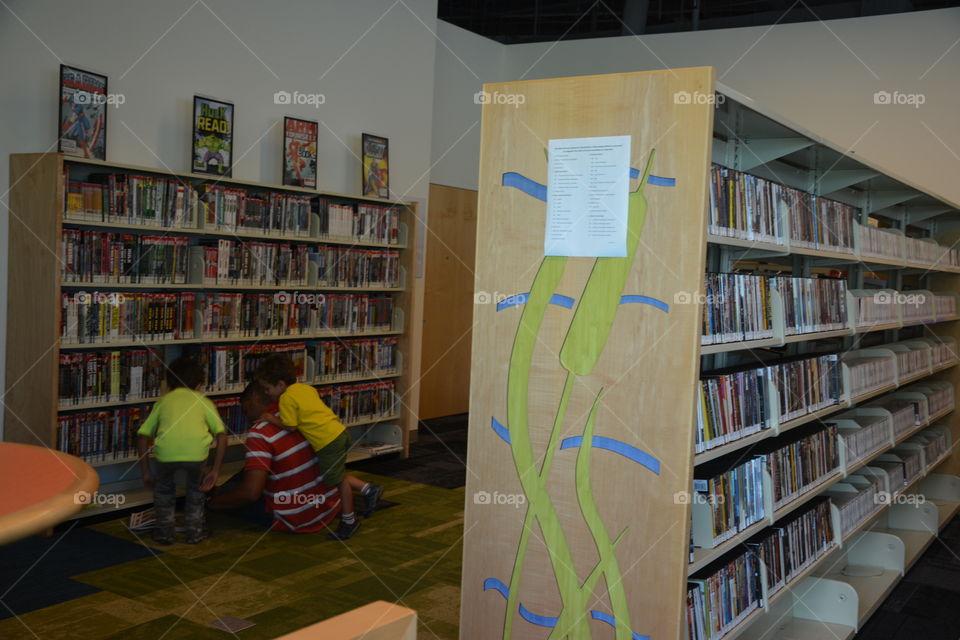 Library Day. A dad and his sons looking for a book in the library 