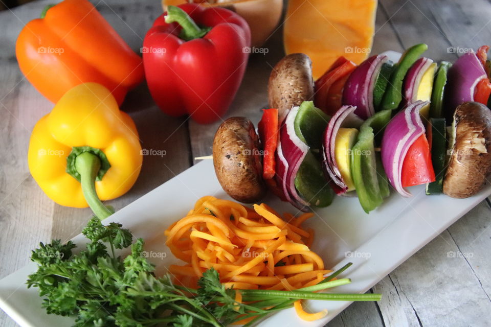 Fresh brightly colored vegetables on white plate on distressed wooden background natural light 