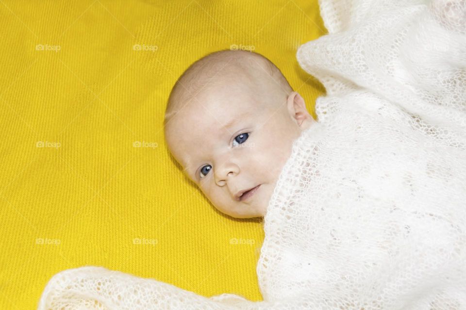 A newborn baby on a yellow and gray background. A photo shoot in the style of Newborn and lifestyle.