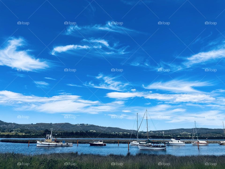 Boats docked in river under blue sky 